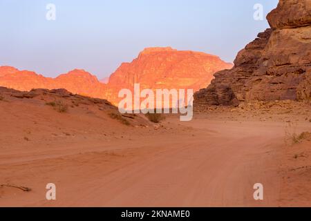 Wadi Rum, Jordanie. Le paysage du désert de sable orange et les montagnes de Jabal Al Qattar à l'aube, au coucher du soleil Banque D'Images