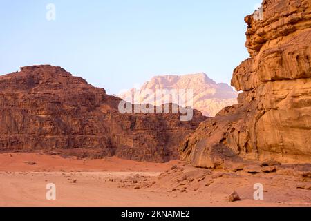 Wadi Rum, Jordanie. Le paysage du désert de sable orange et les montagnes de Jabal Al Qattar à l'aube, au coucher du soleil Banque D'Images