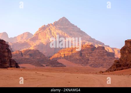 Wadi Rum, Jordanie. Le paysage du désert de sable orange et les montagnes de Jabal Al Qattar à l'aube, au coucher du soleil Banque D'Images