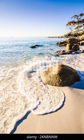 Sable blanc propre et eau de mer mousseuse dans une ambiance sereine de plage tropicale. Binalong Bay, Tasmanie, Australie Banque D'Images