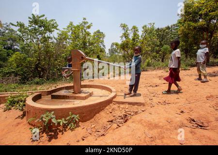 Les élèves boivent de l'eau dans la pompe à eau manuelle communautaire en Afrique Banque D'Images