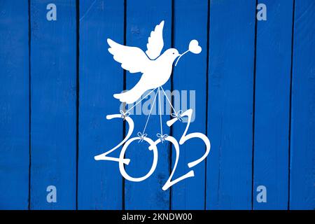 Une colombe porte les numéros de la nouvelle année 2023 sur un fond en bois bleu Banque D'Images