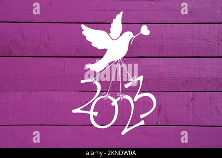 Une colombe porte les chiffres de la nouvelle année 2023 sur fond de bois rose Banque D'Images