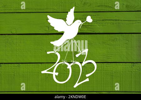 Une colombe porte les numéros de la nouvelle année 2023 sur un fond en bois vert Banque D'Images