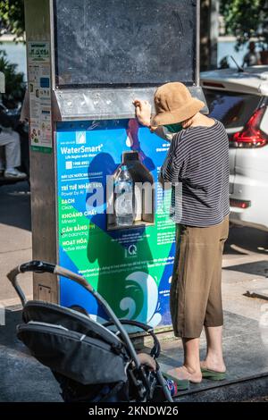 Femme remplissant une bouteille en plastique avec de l'eau potable filtrée gratuite et propre, Hanoi, Vietnam Banque D'Images