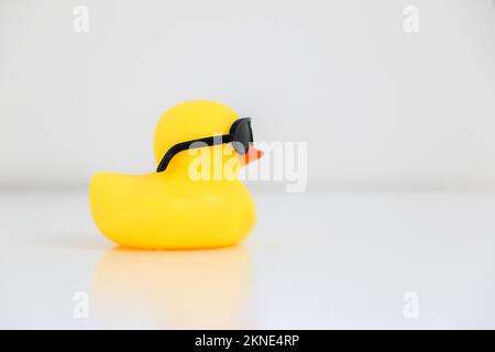 Canard en caoutchouc jaune froid portant des lunettes de soleil noires orientées vers la droite, espace de copie sur la droite. Banque D'Images