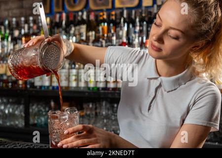 Femme barman qui fait un cocktail d'alcool au bar Banque D'Images