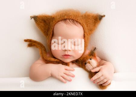 Une jeune fille dans les premiers jours de la vie dans un chapeau de tigre brun avec des oreilles mignonnes. Macro studio portrait d'un enfant sur fond blanc. Vue de dessus. Banque D'Images