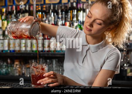 Femme barman qui fait un cocktail d'alcool au bar Banque D'Images