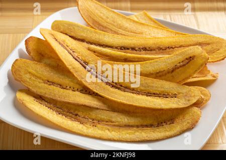 Assiette avec des chips de banane fraîches et cuites au four en gros plan Banque D'Images