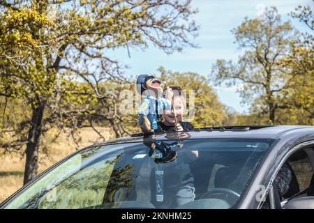 04-17-2020 Bartlesville USA - les jeunes achètent des grins comme il joue avec une marionnette debout dans le toit ouvrant d'un 4x4 à travers le parc animalier d'Oklahoma - sélectif Banque D'Images