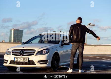 27,10,2022, Pologne. Un gars en Mercedes tient sa main sur le côté et pointe ses pouces vers le haut et vers le bas Banque D'Images