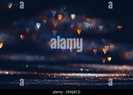 Illuminant les lumières bokeh en forme de cœur de couleur sombre. Fond texturé pour la Saint-Valentin Banque D'Images