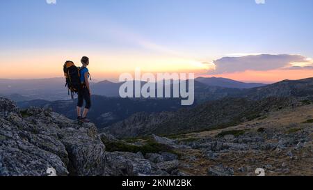 Femme randonneur regardant le coucher du soleil sur le sommet de la montagne Banque D'Images