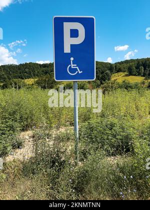 Une photo verticale d'un panneau bleu en forme de rectangle pour le parking handicapés Banque D'Images