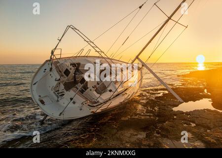 Un yacht, courir sur la crique rocheuse de Siciiy, Italie au coucher du soleil Banque D'Images