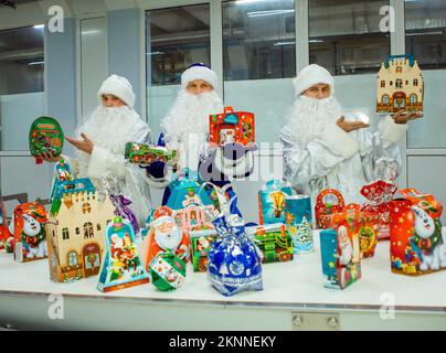 Dnepropetrovsk, Ukraine - 12.08.2017: Les travailleurs d'une usine de confiserie en costumes du Père Noël présentent les produits du nouvel an. Sur les boîtes sont le wor Banque D'Images