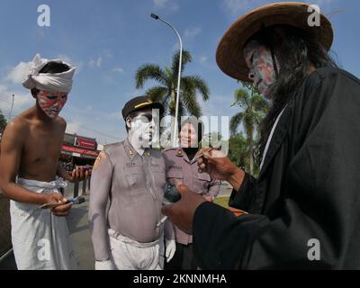 Les artistes peignent les corps de volontaires pour ressembler aux uniformes de la police indonésienne Banque D'Images