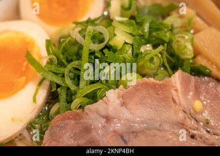 Vue rapprochée sur le poireau de hache, la purée de porc en tranches et l'œuf dur sur la soupe japonaise de nouilles ramen. Banque D'Images