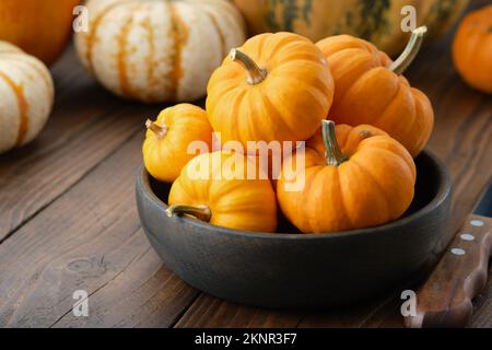 Plusieurs petits citrouilles dans un bol en bois sur une table de cuisine. Banque D'Images