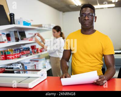 Portrait d'un employé positif de la maison d'impression avec des projets entre les mains Banque D'Images