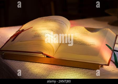 La lumière du soleil brille par des vitraux sur le livre de prière français ouvert sur table d'autel. Banque D'Images