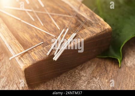 Tenez-vous debout avec les aiguilles d'acupuncture sur fond en bois, gros plan Banque D'Images