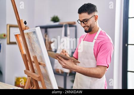Jeune artiste homme arabe souriant et confiant, dessin au studio d'art Banque D'Images