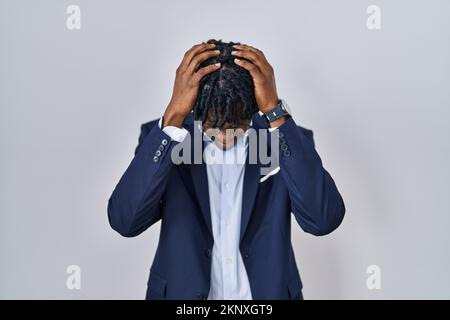 Jeune homme africain avec des dreadlocks portant une veste d'affaires sur fond blanc souffrant de maux de tête désespérés et stressés parce que la douleur et migrai Banque D'Images