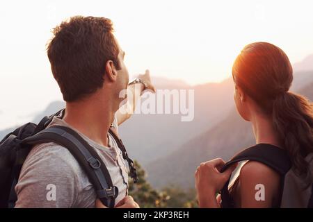 On s'y dirigea vers ce point... Un jeune homme qui pointe vers l'horizon tandis que sa petite amie regarde. Banque D'Images