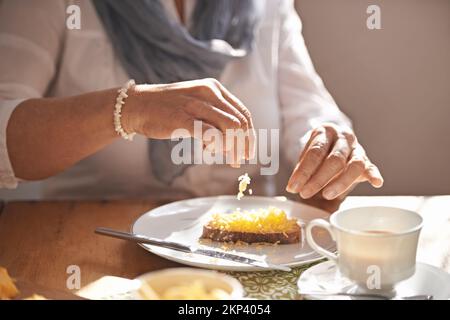 Thé et lumière lunch...delicious. Vue rognée sur les mains des femmes mettant du fromage sur du pain pour le déjeuner. Banque D'Images