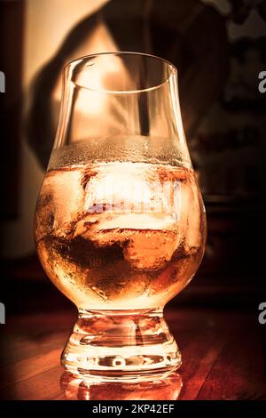 Vue à angle bas sur un délicieux verre de cognac dans un demi-verre plein de neige sur le comptoir de barre en bois sombre. Boissons de classe Banque D'Images