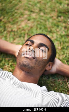 Profitez de votre séjour à l'extérieur. un beau jeune homme couché sur l'herbe à l'extérieur. Banque D'Images