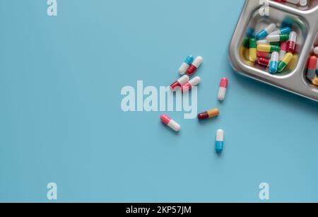 Au-dessus de la vue des pilules colorées de capsule d'antibiotique sur un plateau et un fond bleu. Résistance aux antibiotiques. Médicaments antimicrobiens. Médicaments sur ordonnance. Banque D'Images