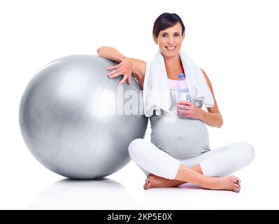 Garder la forme, jusqu'à son dernier trimestre. Une mère enceinte souriant avec une balle pilates alors qu'elle est isolée sur le blanc. Banque D'Images