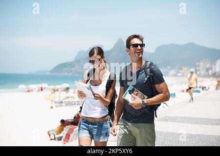 Avec elle à mes côtés, ces vacances seront super. un jeune couple qui descend une belle plage. Banque D'Images