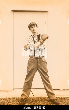 Vintage sport concept d'un beau gars portant de vieux gants de boxe devant la porte de l'arène sportive. Prêt pour l'action Banque D'Images