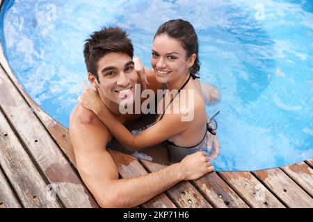 Des vacances joyeuses. Portrait d'un jeune couple attrayant se relaxant dans une piscine. Banque D'Images