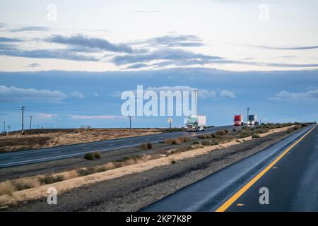 Convoi de semi-remorques industrielles de grandes rigs avec phares allumés et semi-remorques transportant des marchandises commerciales se déplaçant sur la route de la Banque D'Images