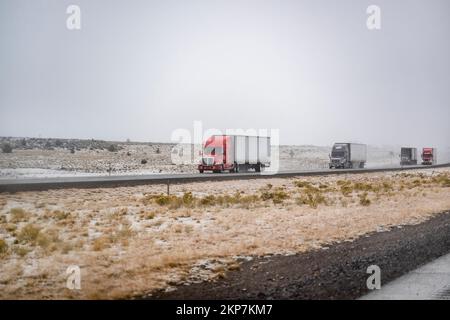 Convoi de gros engins de manutention semi-remorques avec semi-remorques transportant des marchandises commerciales sur une route glissante pendant un hiver sno Banque D'Images