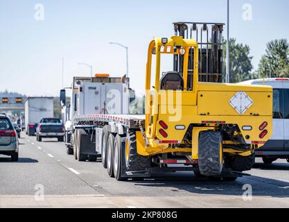 Semi-remorque industrielle bordeaux classique long-courrier grande plate-forme de forage à cabine allongée semi-remorque semi-camion caisses de transport sur le plateau semi-remorque fonctionnant sur le étroit wi Banque D'Images