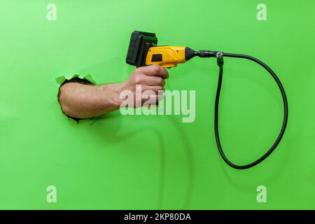 Appareil-photo d'endoscope dans une main mâle isolée sur le vert Banque D'Images