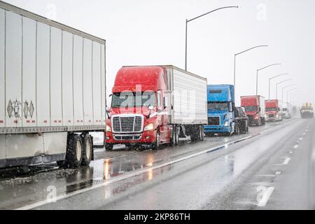 Convoi de gros engins de manutention semi-remorques avec semi-remorques transportant des marchandises commerciales sur une route glissante pendant un hiver sno Banque D'Images