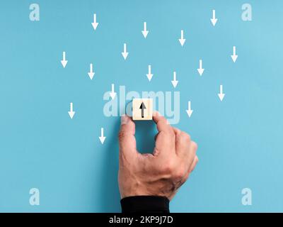 Unique, pensez différent, individualité. Nagez contre le ruisseau et sortez de la foule. Main mâle plaçant un bloc de bois avec un point d'intérêt opposé Banque D'Images