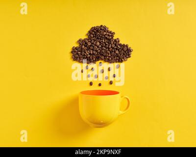 Concept de café de pluie. Grains de café en forme de nuage de pluie et gouttes de pluie qui pleuvaient vers la tasse de café sur fond jaune. Banque D'Images