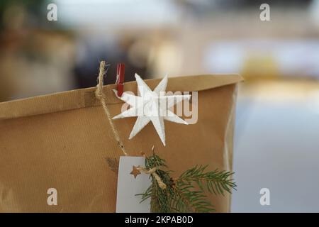 Boîte cadeau de Noël en papier recyclé avec arbre de noël en arrière-plan. Banque D'Images