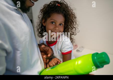 Petite fille mignonne et son père joyeux à la laverie Banque D'Images