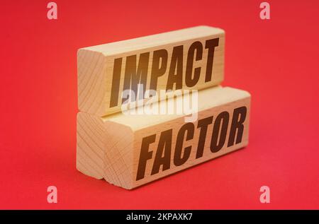 Concept d'affaires et d'économie. Sur fond rouge, blocs de bois avec inscription - FACTEUR D'IMPACT Banque D'Images