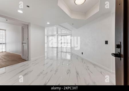 Un grand couloir ensoleillé avec des carreaux de marbre et des murs blancs dans un design moderne Banque D'Images