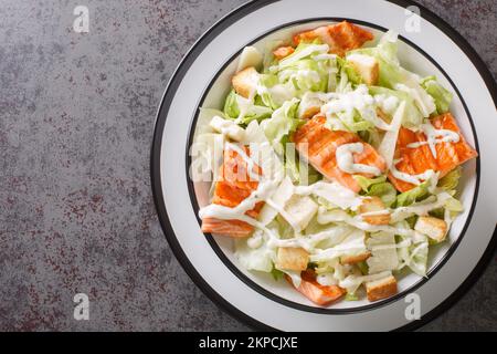 Salade César au saumon grillé avec croûtons, parmesan, vinaigrette César sur l'assiette de la table. Vue horizontale du dessus Banque D'Images